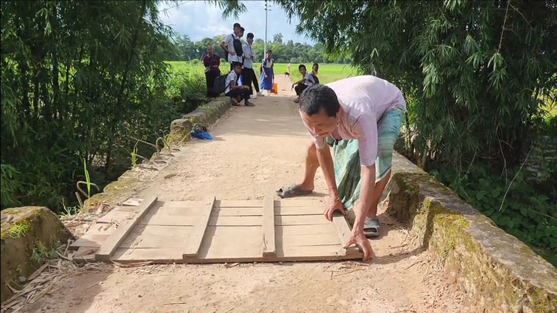 A local resident places a wooden plank over a large hole in the Panchhari culvert to help pedestrians cross safely. Photo: Biplab Talukder/V7N